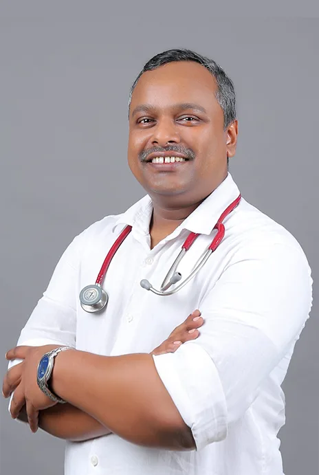 Dr. Anuraj Appukuttan, Consultant Laparoscopic and General Surgeon at Havisha Hospital, smiling with arms crossed and a red stethoscope over a white shirt.
